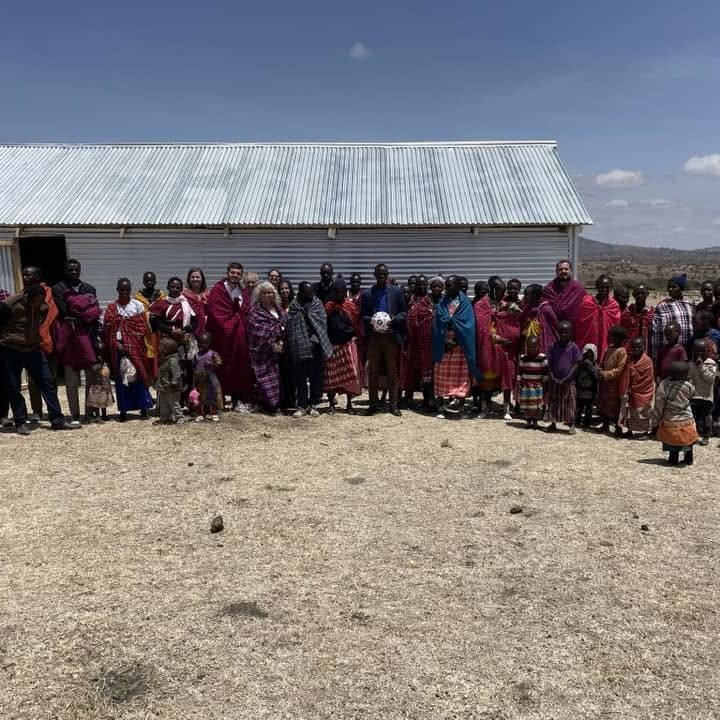 A large group of villagers and mission team standing outside a metal church building